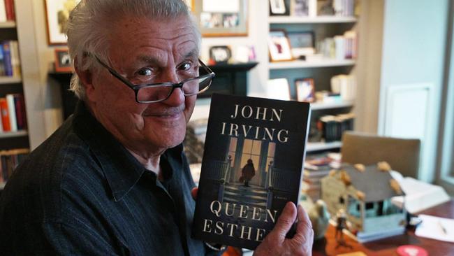 John Irving in Kamera lächelnd mit neuem Buch "Queen Esther" in der Hand