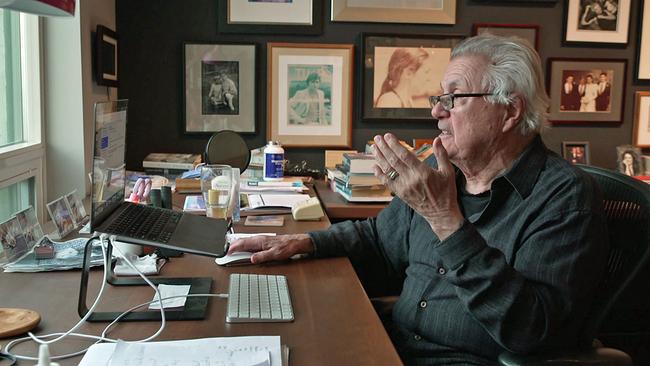 John Irving am Schreibtisch redend