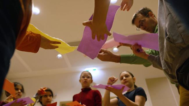 Schulkinder machen mit Papierstreifen Geräusche