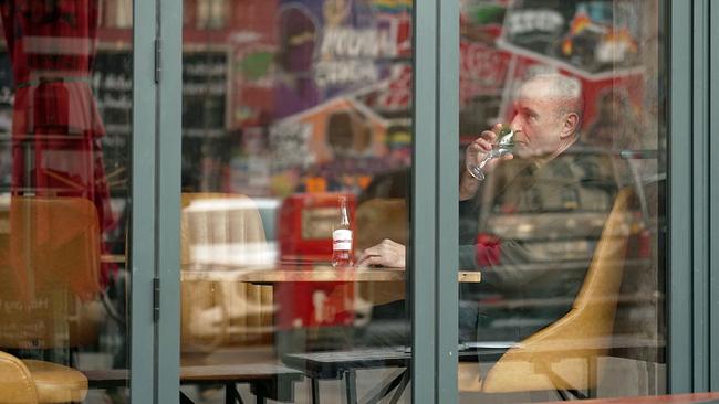Norbert Gstrein von der Straße durch Fenster trinkend in Kaffeehaus