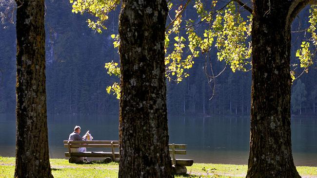 Zeitunglesender auf Bankerl am See