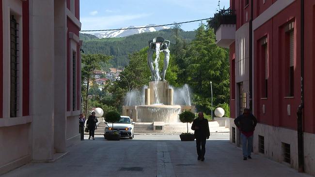 L' Aquila Gasse mit Blick auf Springbrunnen und Berge im Hintergrund