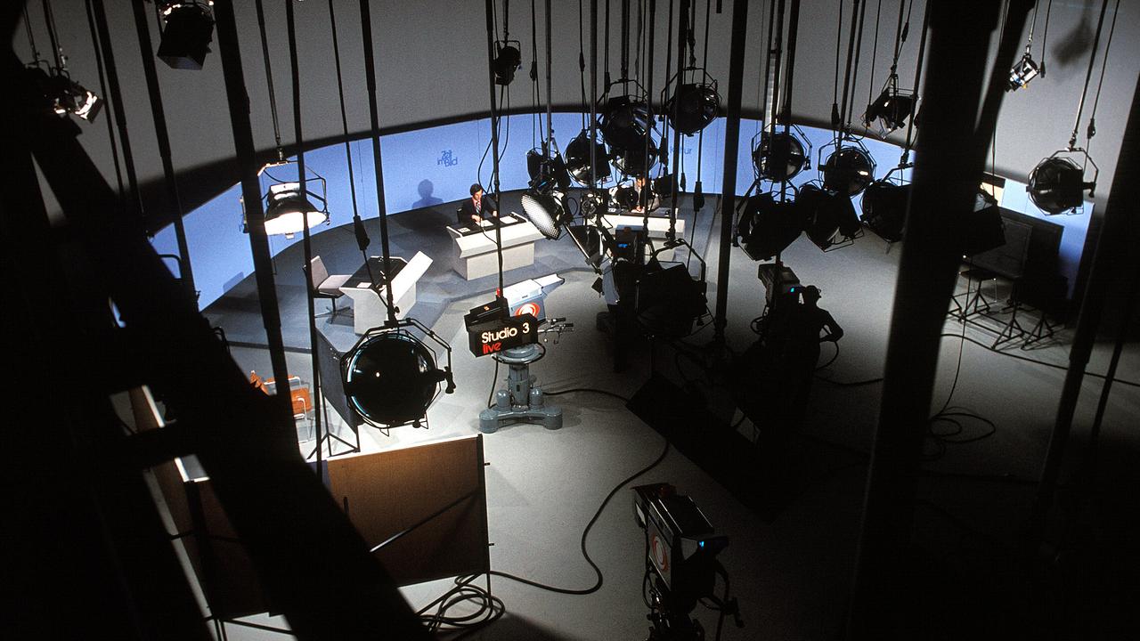Eine Totale des ORF-Newsrooms 1980 zeigt mehrere Moderatoren am Nachrichtentisch unter einer Vielzahl von Scheinwerfern.