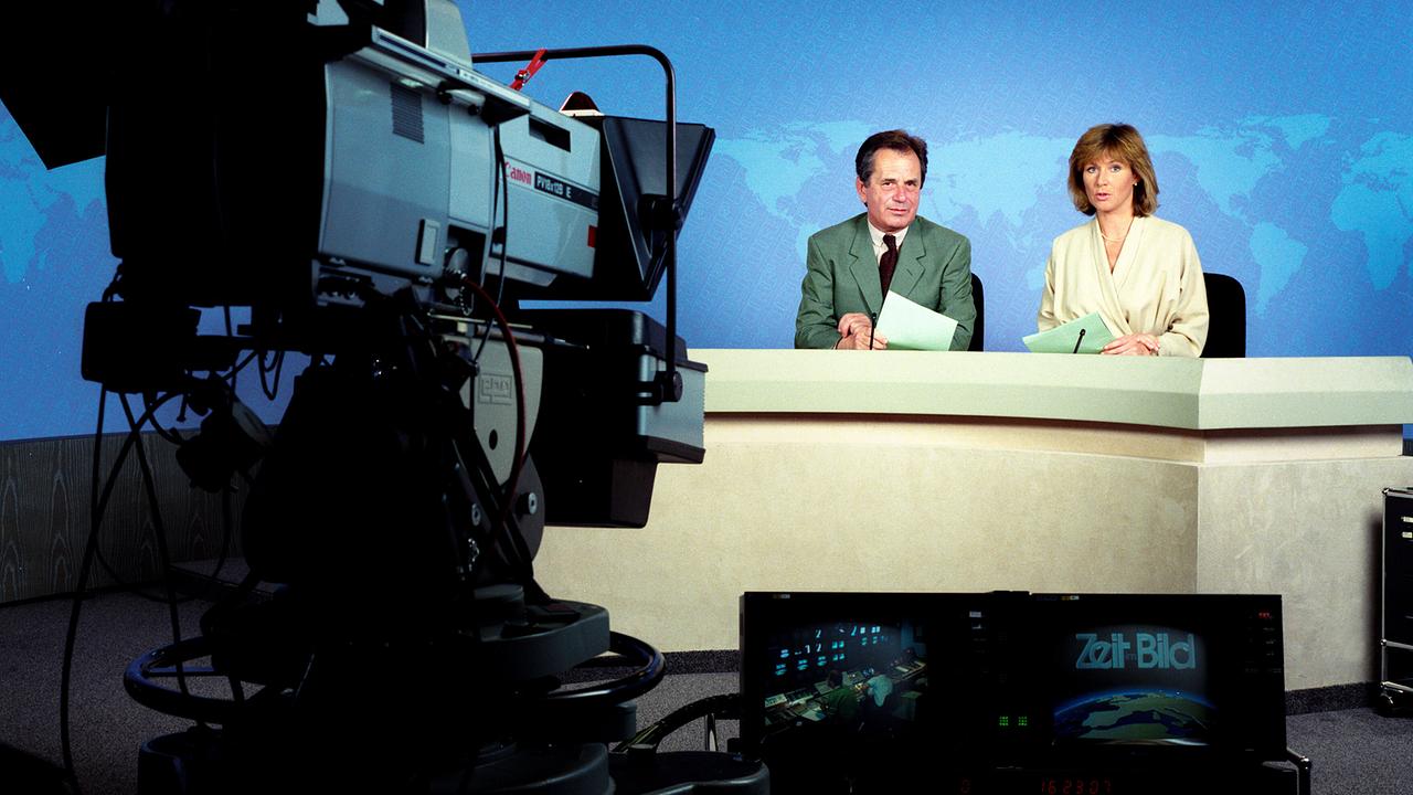 Horst Friedrich Mayer und Ricarda Reinisch sitzen am „Zeit im Bild“-Tisch, während eine Kamera im Vordergrund auf sie gerichtet ist.