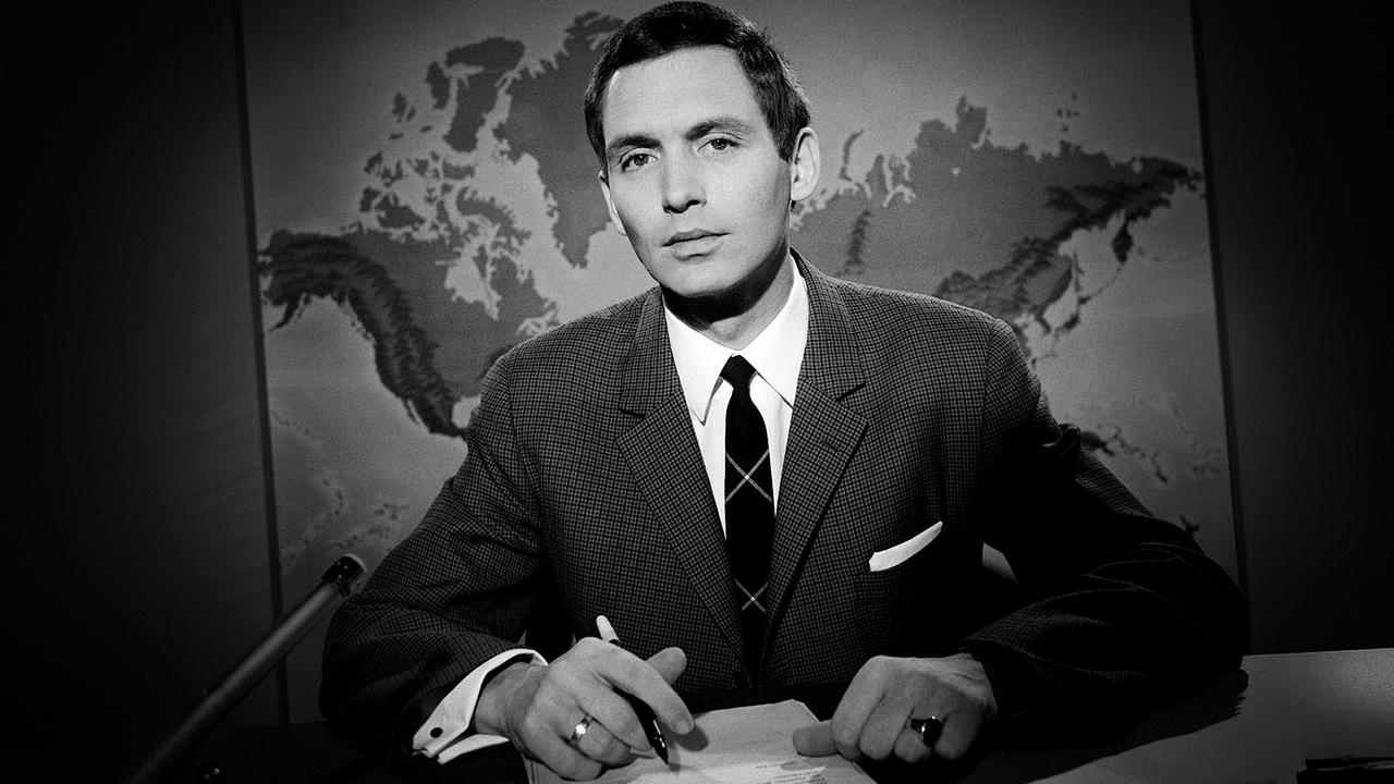 Schwarz-Weiß-Aufnahme von Walter Richard Langer, der in den 1960er-Jahren am ""Zeit im Bild"-Schreibtisch vor einer Weltkarte sitzt.