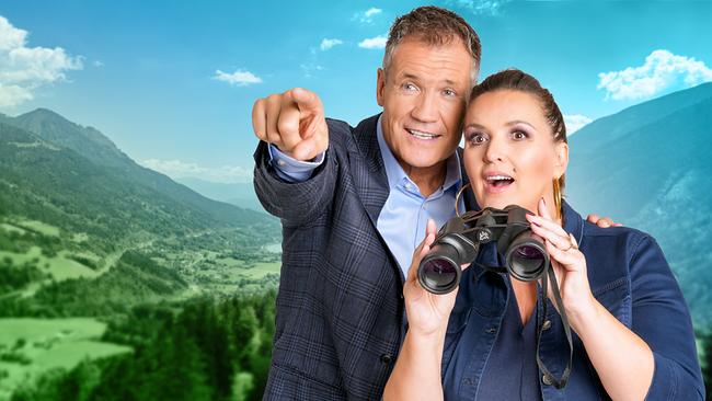 Armin Assinger und Barbara Karlich mit Fernrohr stehen vor einer Berglandschaft und schauen  in die Ferne