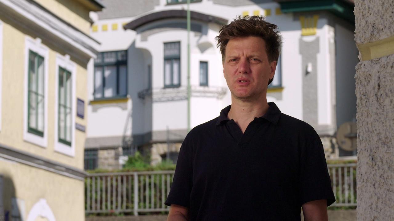 Artur Bodenstein steht im Freien vor Gebäuden aus der Jahrhundertwende in Klosterneuburg