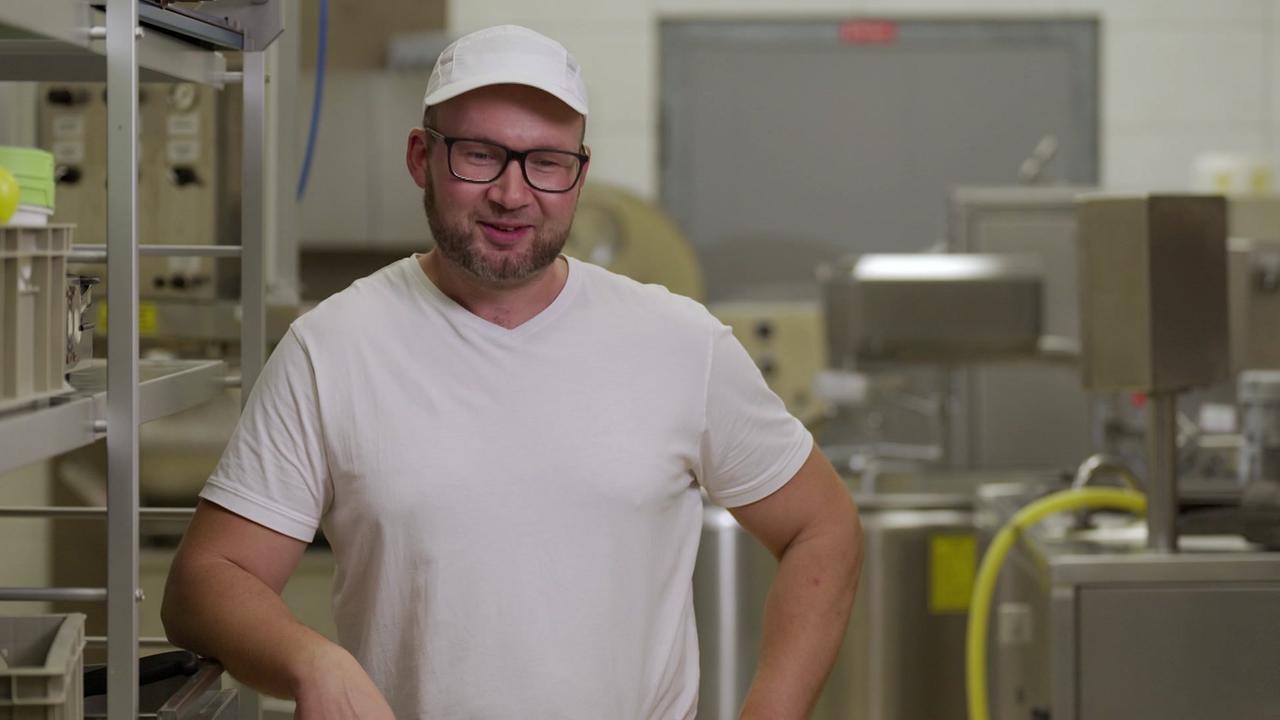 © Satel/ORF Hans Gabauer steht in Arbeitskleidung in seiner Käserei zwischen Edelstahlmaschinen