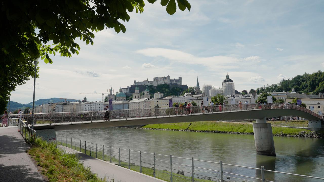 © ORF Barbara Karlich überquert eine Brücke über die Salzach, im Hintergrund die Festung Hohensalzburg