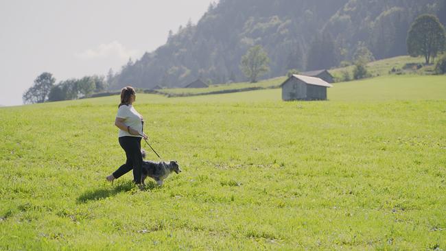 Barbara Karlich auf einer Wiese mit Hund unterwegs