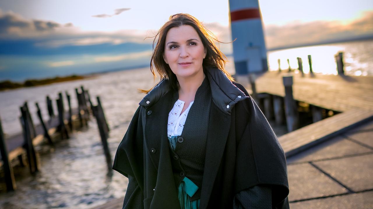 Barbara Karlich steht vor dem Leuchtturm in Podersdorf