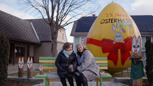 Barbara Karlich und ihre Mutter Katharina sitzen auf einer Bank, im Hintergrund ein riesiges Osterei