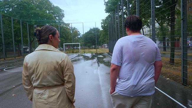 © ORF Fußballkäfig umgeben von Bäumen, es regnet - die Redakeurin und ein Jugendlicher im nassen T-Shirt unterhalten sich