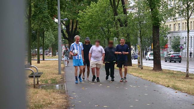 © ORF Allee in einerStraße, eine Gruppe Jugendliche gehen mit ihren Betreuern entlang -ein Betreuer hält einen Fußball inder Hand