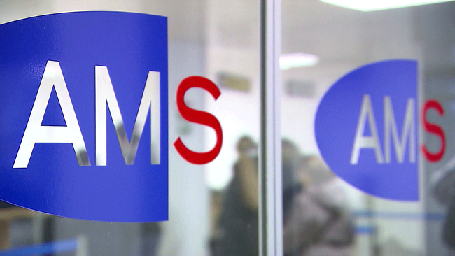 AMS Logo; rote Schrift auf blauem Hintergrund auf einer Glastüre