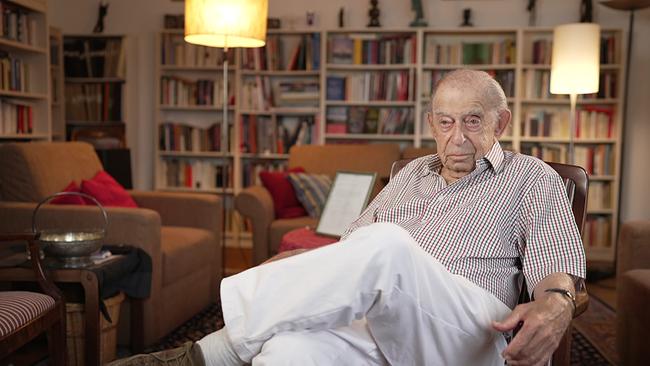 Der 97jähre Paul Lendvai sitzt in seinem Wohnzimmer auf einem Stuhl, im Hintergrund Bücherstellagen, 2 Lampen und Sofasessel