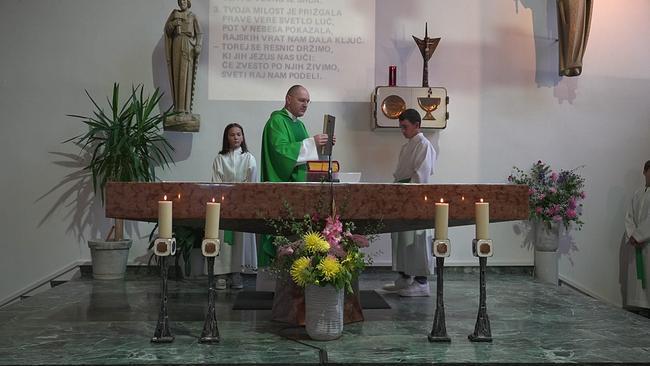 © ORF Altar in einer Kirche, dahinter steht ein Priester bei der Wandlung, flankiert von 2 Ministranten, eine slowenischsprachige Inschrift ist an der Wand zu sehen