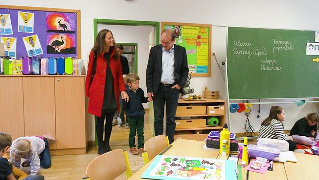 © ORF Klassenzimmer in der Türe steht ein Elternpaar mit ihrem Sohn und schauen sich um, weiter Kinder spielen auf dem Boden