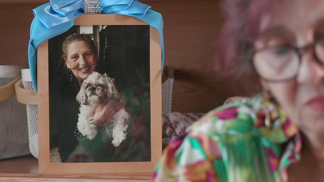 gerahmtes und geschmücktes Foto von Ceija Stojka auf eine Anrichte, davor ist ihre Schwiegertochter Nuna Stojka unscharf zu sehen