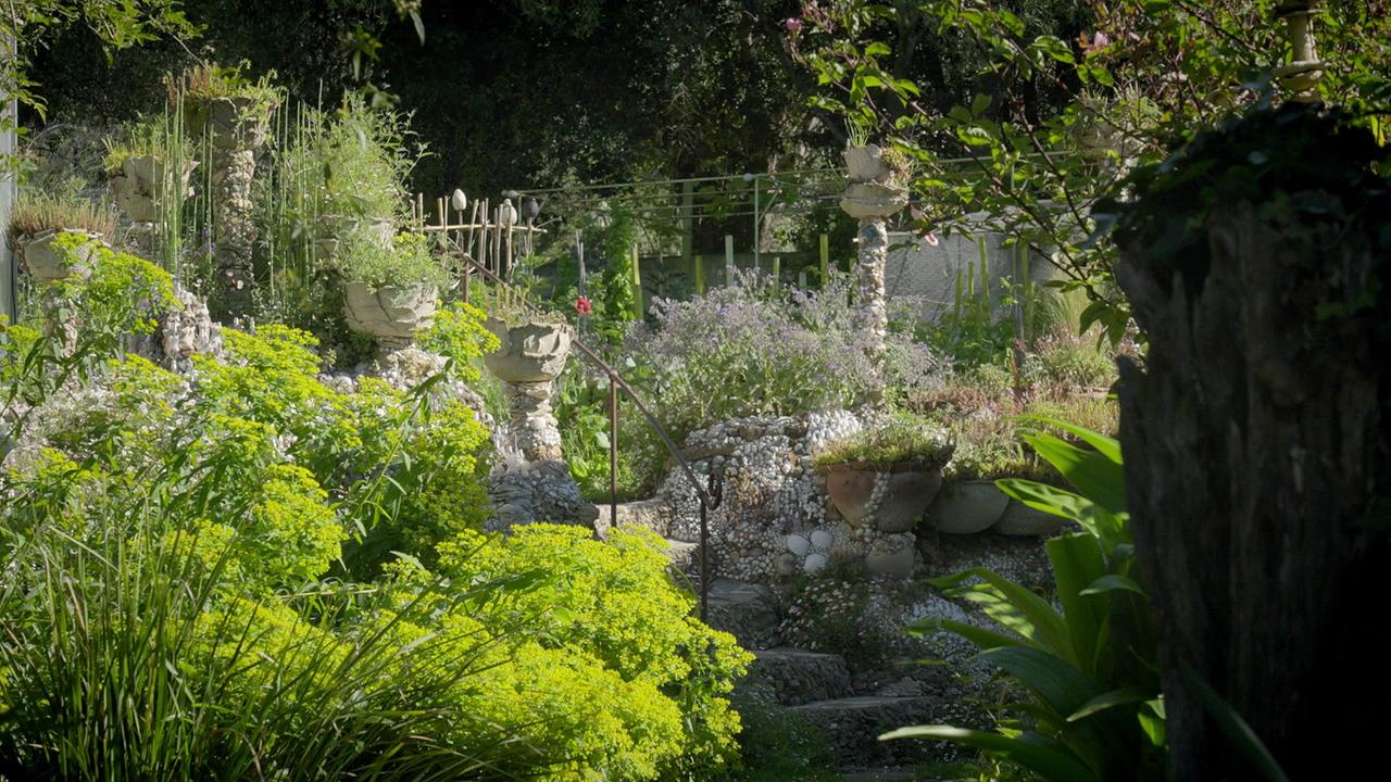 © ORF/Ralph Huber-Blechinger Üppig bepflanzter Garten mit mehreren Tontöpfen, Steinmauern und dichtem Grün