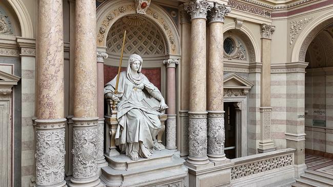 © ORF Weiße Statue der Göttin Justitia im Justizpalast, sie sitzt auf einem Thron mit einem Schwert in der Handund ist von Opulenten Säulen umgeben