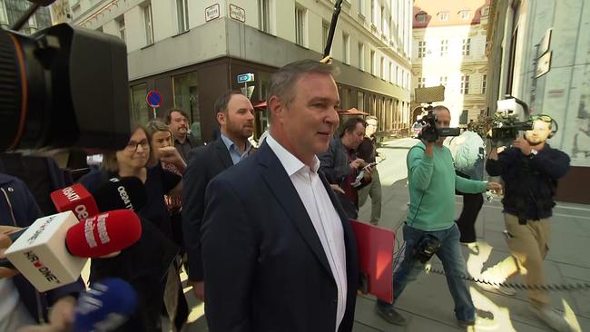 Andreas Babler auf der Straße gehend,  umgeben von Kameraleuten und Journalisten, die ihm einige Mikros entgegenhalten