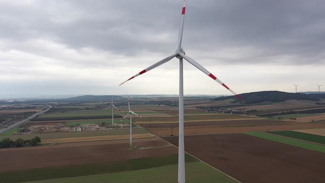 mehrere Windräder stehen auf abgeernteten Feldern