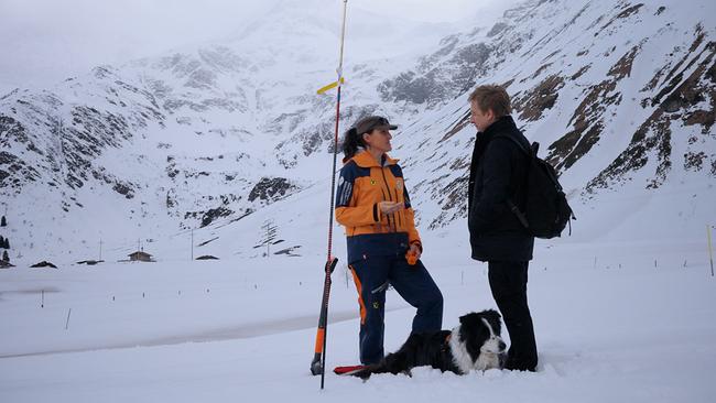 Max Müller und Hundeführerin Cornelia Pfund-Stockinger im Gespräch vor winterlicher Kulisse