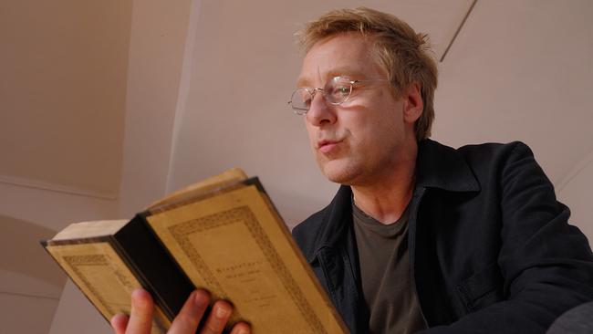 Max Müller hält ein Sagenbuch in der Hand und liest daraus vor