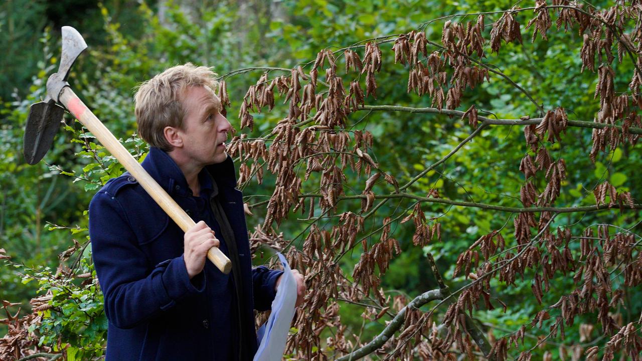 Max Müller streift mit einer Axt durch den Wald