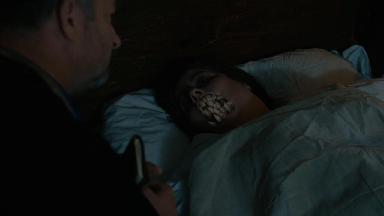 Die Moserin liegt im Bett, ein Priester an ihrer Seite. Ihr wachsen Zähne, damit kann sie die Beichte nicht mehr ablegen.