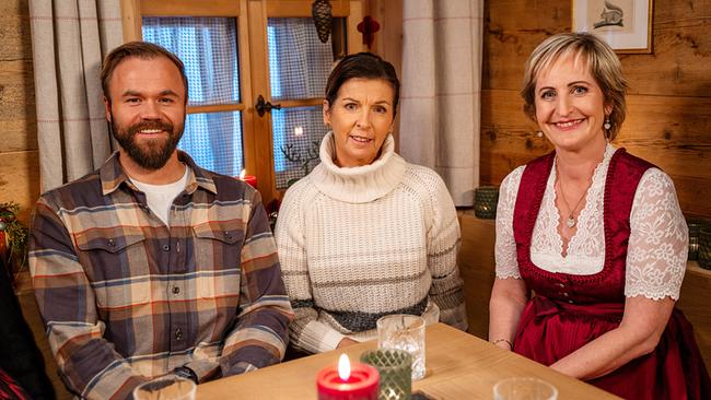 Markus Schairer (Snowboardcross-Weltmeister 2009), Anita Wachter (Olympiasiegerin 1988) und Moderatorin Martina Köberle sitzen gemeinsam an einem Tisch in einer rustikalen Bauernstube.