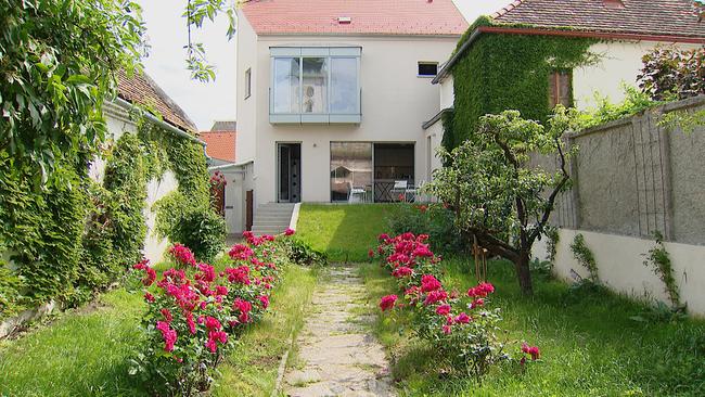 Haus mit schmalem Garten davor, mit blühenden Rosen