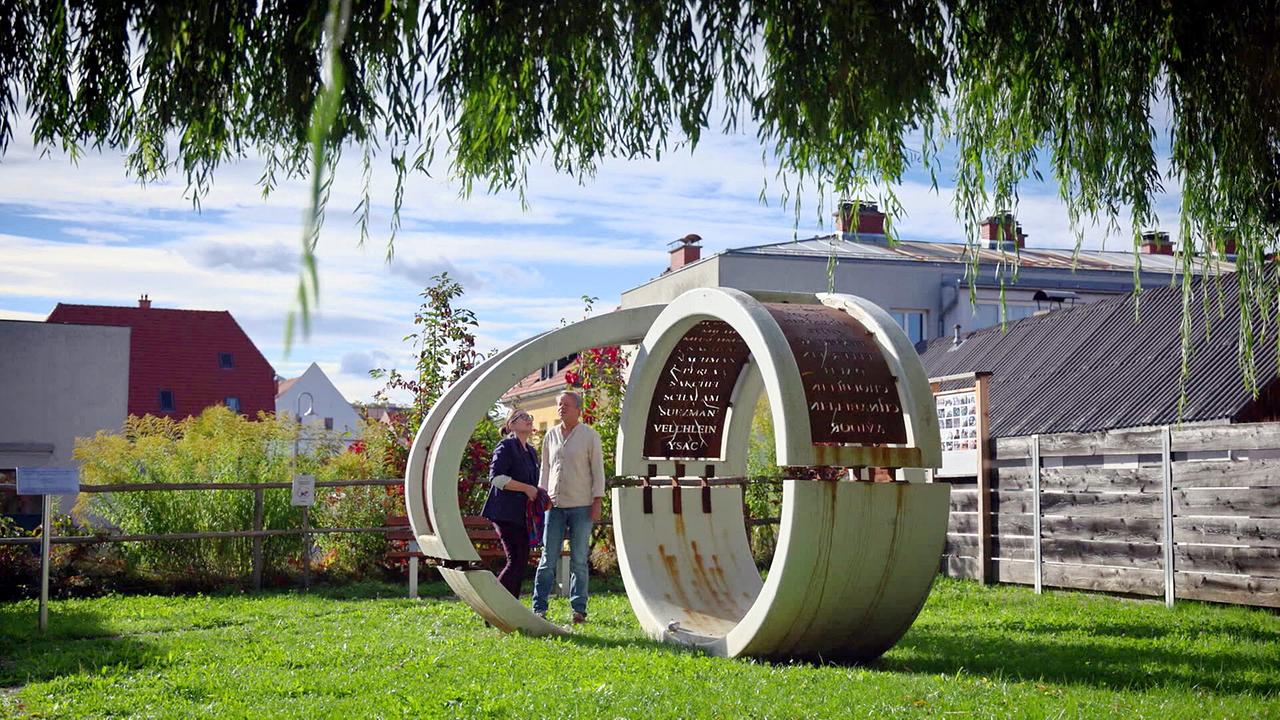 © ORF/Martin Gerhartl Zwei Menschen stehen bei dem modernen Skulpturen-Denkmal "Ringe der Erinnerung - Denkmal für die einstige jüdische Gemeinde von Judenburg" im Freien.