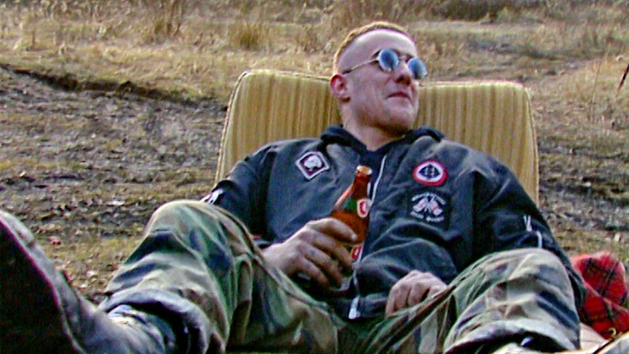 © ORF Skinhead-Neonazi sitzt im Freien auf einem Coachsessel und hält eine Bierflasche, 1992