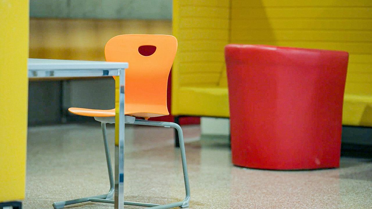 © ORF/HolyScreen Media Eine moderne Sitzecke mit einem orangefarbenen Stuhl an einem Schreibtisch und gelben Sitzelementen in einer Schule