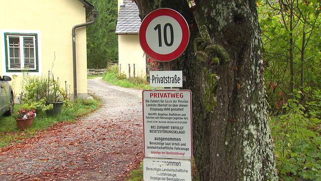 Privatstraße mit mit einem Verkehrsschild für Geschwindigkeitsbeschränkung 10 km/h an einem Baum