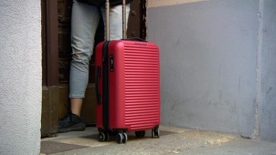 Eine Touristin mit einem Rollkoffer vor einem Hauseingang