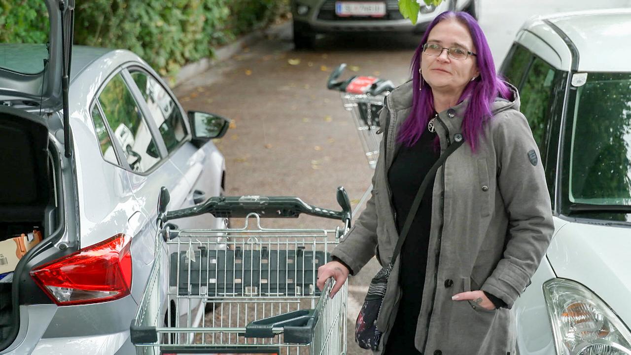 © ORF Alleinerzieherin Silke beim Lebensmitteleinkauf in Freilassing/Deutschland steht mit ihrem Einkaufswagen zwischen Autos am Parkplatz.