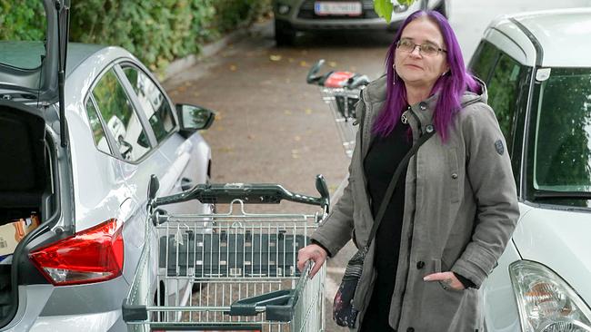 Alleinerzieherin Silke beim Lebensmitteleinkauf in Freilassing/Deutschland steht mit ihrem Einkaufswagen zwischen Autos am Parkplatz.