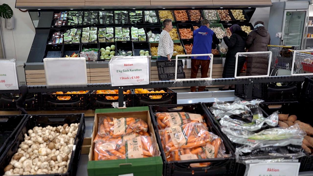 Mehrere Kundinnen und Kunden stehen im "Soogut" Sozialmarkt in St. Pölten an einer großen, gut gefüllten Gemüse- und Obstabteilung.