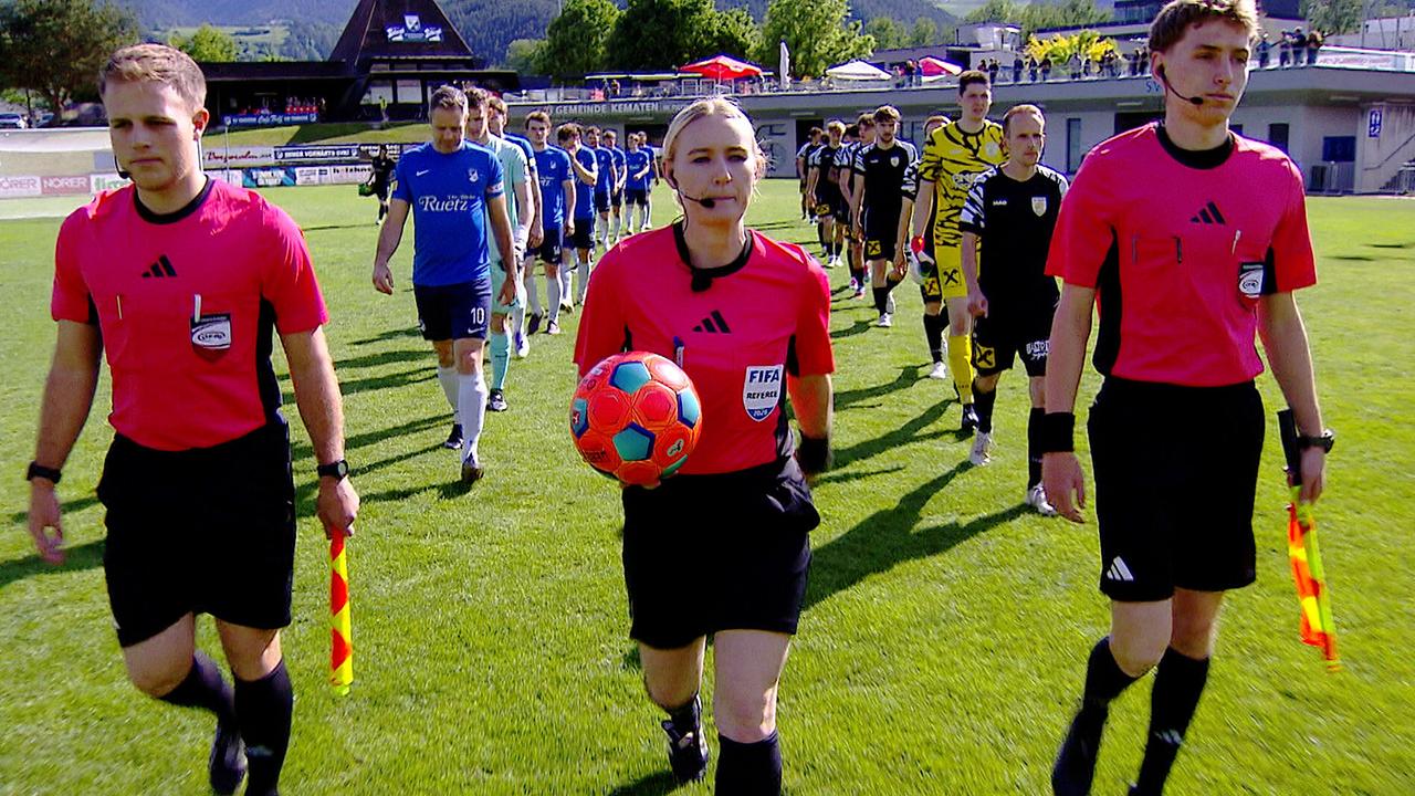 Schiedsrichterin Olivia Tschon betritt gemeinsam mit zwei Fußballmannschaften das Spielfeld vor Beginn eines Spiels.