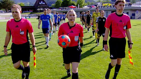 Schiedsrichterin Olivia Tschon betritt gemeinsam mit zwei Fußballmannschaften das Spielfeld vor Beginn eines Spiels.