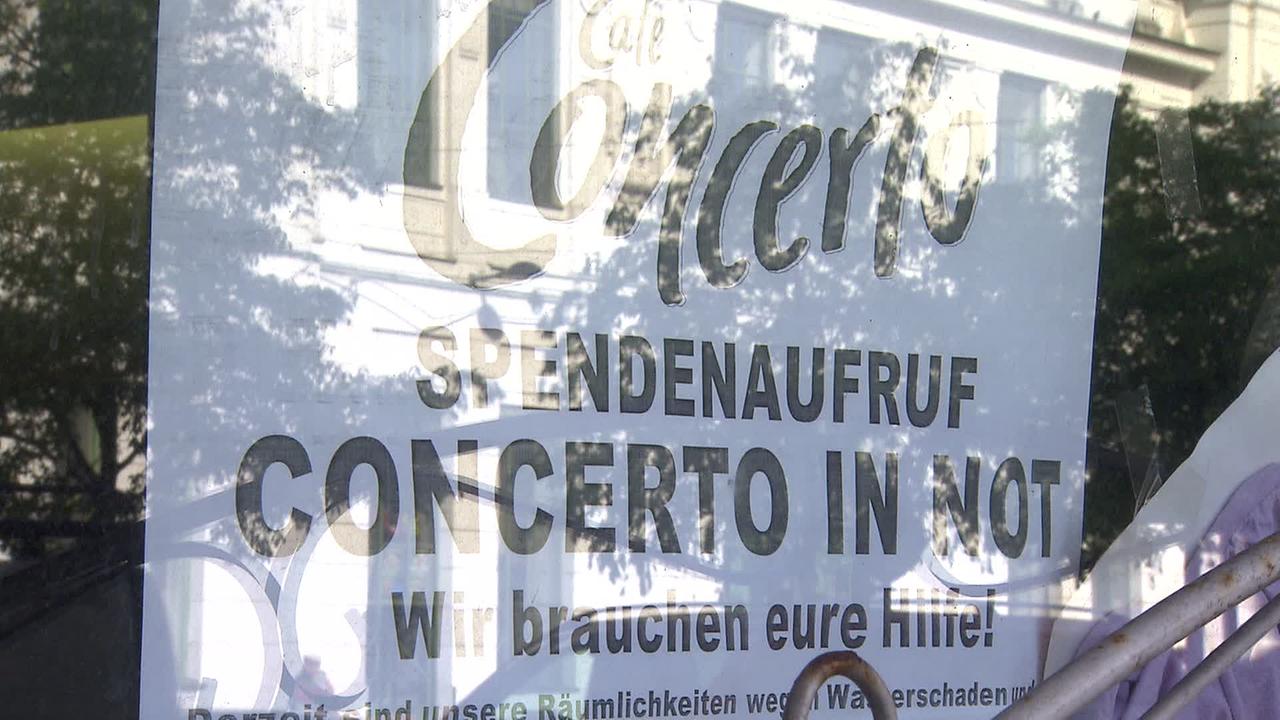 Am Bild sieht man ein Plakat hinter einer spiegelnden Auslagenscheibe. Am Plakat steht: Café Concerto Spendenaufruf. Concerto in Not. Wir brauchen eure Hilfe.
