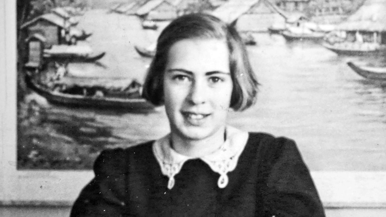 Eva Geiringer in Amsterdam: Die Schülerin sitzt an einem Tisch und schreibt in ein Heft, hinter ihr hängt ein großes Wandbild mit Booten und Häusern.