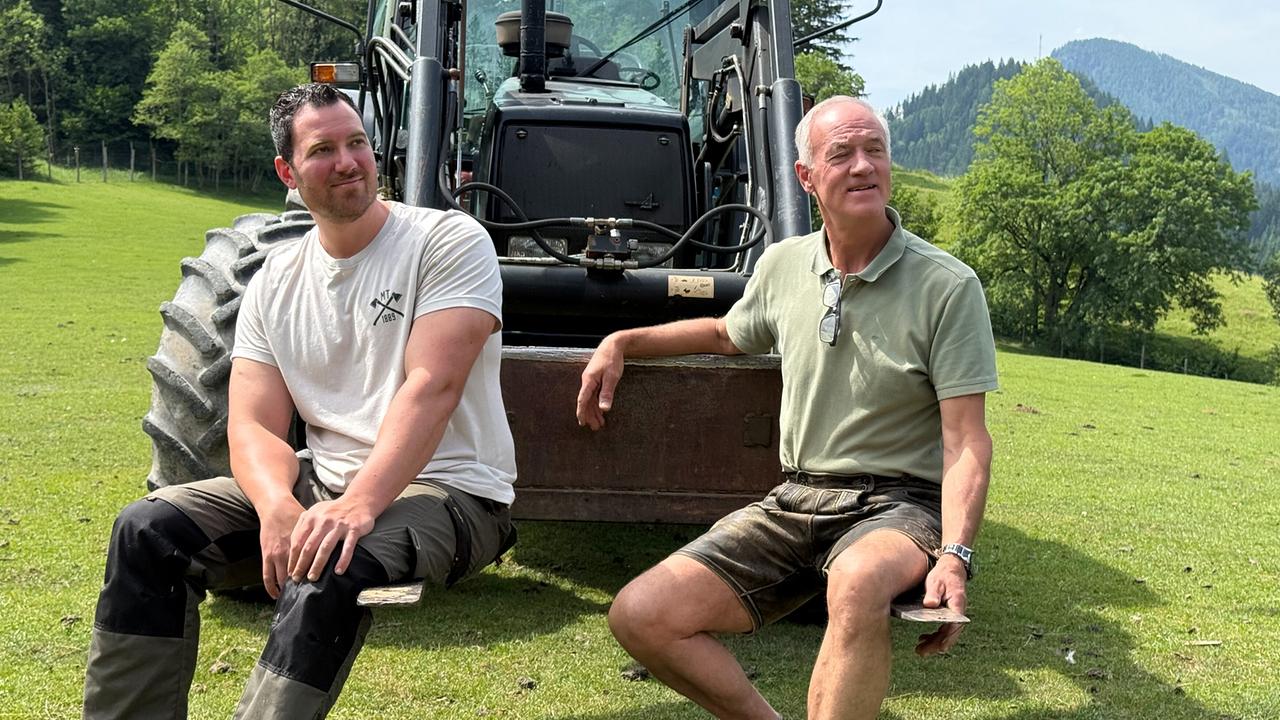 Franz und Michael Stromminger vor einem Traktor auf einer grünen Wiese