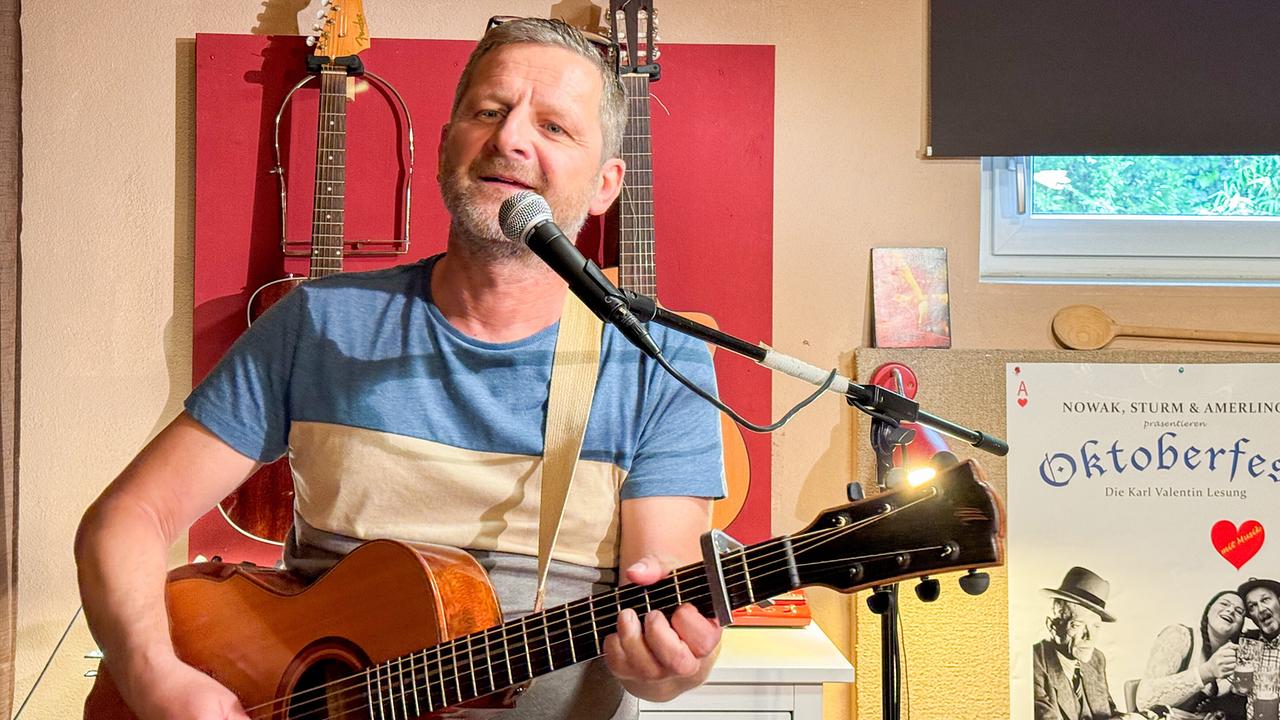 Christoph Amelin spielt stehend Gitarre. 
