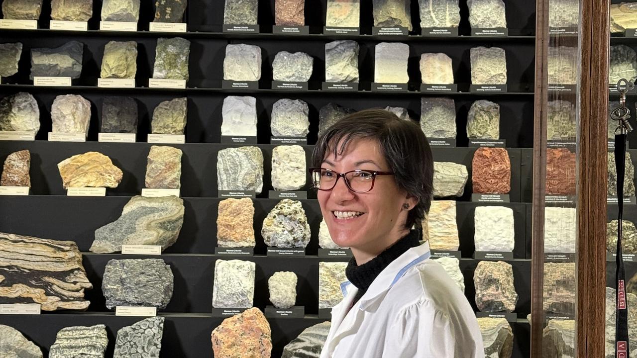 Geologin Lidia Pittarello im Naturhistorischen Museum vor einer Wand mit Gesteinsproben