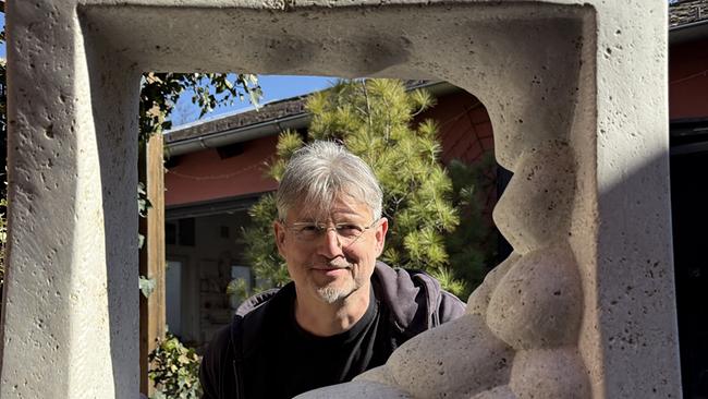 Bildhauer Reinhard Winter schaut durch eine Steinskulptur