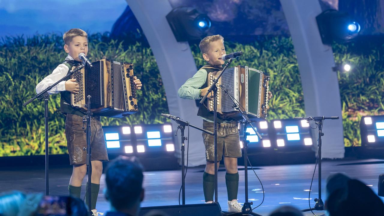 © ORF/Landesstudio Steiermark/Regine Schoettl Die Buben Alexander Pachatz und Lukas Deutschmann in Tracht spielen steirische Harmonika und singen auf einer Bühne.